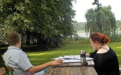 Außenanlage Villa Fohrde mit Blick auf Havel. Zwei Personen an Tisch.